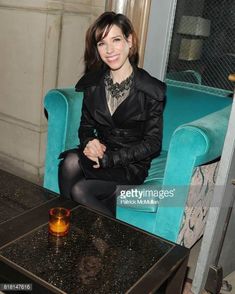 a woman sitting on a blue couch in front of a table with a glass candle