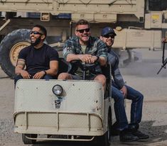 three men are riding in an old car