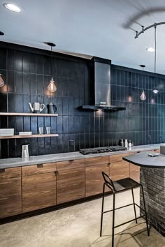 a kitchen with an island and bar stools next to the counter top, along with several lights hanging from the ceiling