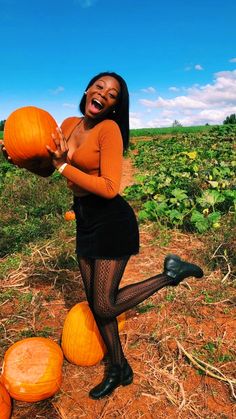 a woman is posing with pumpkins in the field