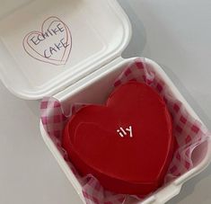 a red heart shaped cake in a box with writing on the lid that says i love you