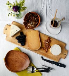 cheese and nuts are on a cutting board with utensils