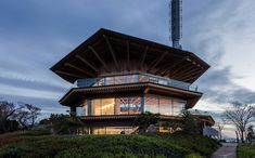 a tall building sitting on top of a lush green hillside next to a forest covered hillside