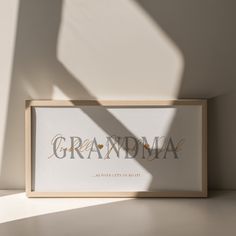 a framed photograph with the word grandma in gold foil on it next to a white wall