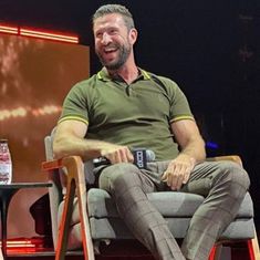 a man sitting on top of a chair in front of a screen