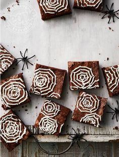 chocolate brownies with white frosting and spider webs on top, sitting on a table