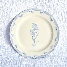 a blue and white plate with flowers on it sitting on a tablecloth covered surface