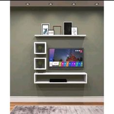 a flat screen tv sitting on top of a white wall mounted entertainment center in a living room