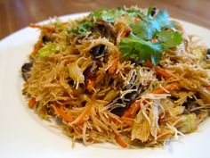 a white plate topped with lots of food on top of a wooden table next to a fork