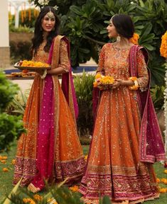 two women dressed in orange and pink outfits