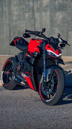 a red and black motorcycle parked next to a wall