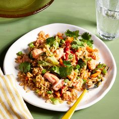 a white plate topped with rice and veggies next to a glass of water