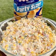 a bowl filled with corn chips next to a bag of party size potato chips