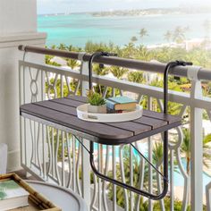 a balcony with a potted plant and books on the table, next to an ocean view