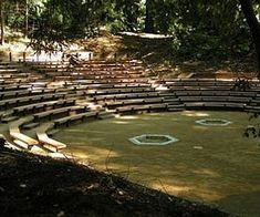 an outdoor seating area in the middle of a park with trees and benches around it