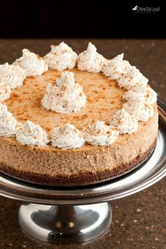 a cheesecake with whipped cream on top is sitting on a cake platter, ready to be eaten