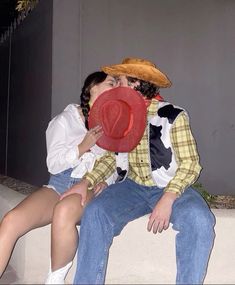 a man and woman sitting next to each other with a red hat on their heads