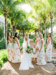 a group of women standing next to each other in front of palm trees and flowers