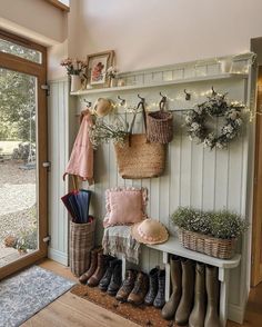 the entryway is decorated with baskets, umbrellas, and boots on display next to an open door