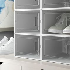 a pair of white sneakers sitting on top of a shelf in front of a painting