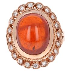 This breath taking and Victorian inspired ring has a 15.77 Carat Oval Cabochon Cut Spessartine Garnet. Spessartines are natural gemstones that belong to the Garnet family. The ring also has 20 Round Cut Diamonds that weigh 0.41 carats. The clarity and color of the diamonds are VS-H. The total carat weight of the ring is 16.18 Carats. The Spessartine is 12 mm x 14 mm and has a royal burnt orange color which holds value. Carefully curated in 14K Rose Gold and is a size 7.5 Ring sizing can be done Intuitive Thinking, Spessartine Garnet, Baked Clay, Sapphire Cocktail Ring, Garnet And Diamond Ring, Rose Stone, Color Of The Day, Spessartite Garnet, Burnt Orange Color