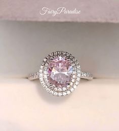 a pink diamond ring sitting on top of a white box