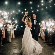 a bride and groom holding sparklers in their hands as they walk down the aisle