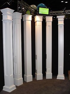 four white pillars are standing in the middle of a room with black walls and carpet