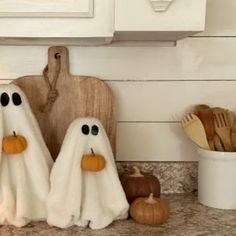 three white ghost towels sitting on top of a counter next to wooden utensils