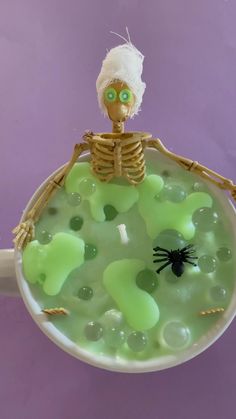 a skeleton is sitting in a bowl filled with green liquid and bubbles, as if it were floating or floating on the water