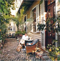 a man sitting at a table in front of a house with his dog on the patio