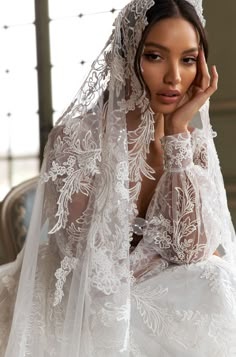 a woman in a white wedding dress with a veil over her head and hands on her face