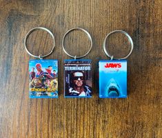 three keychains with movies on them sitting next to each other