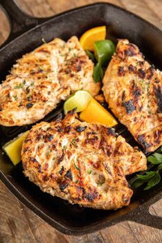 grilled chicken in a cast iron skillet with lemon wedges and parsley