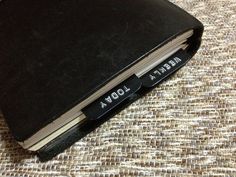 an open black book sitting on top of a brown cloth covered floor next to a computer mouse