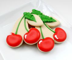 a cookie decorated with cherries and leaves on a plate