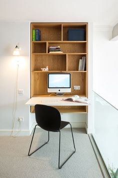 a desk with a computer on top of it in front of a bookshelf