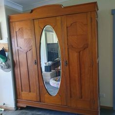 a large wooden armoire with a mirror on it