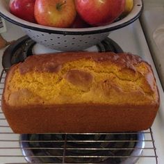 a loaf of bread sitting on top of a metal rack next to an apple pie