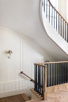 an empty room with wood flooring and white walls, next to a spiral staircase