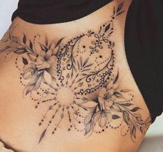 a woman's stomach with an intricate tattoo design on the side, and flowers in the center