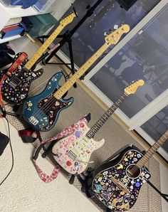 four guitars are lined up on the floor