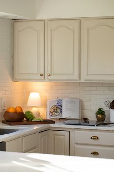 a kitchen with white cabinets and an open book on the counter next to a sink