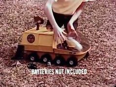 a young boy is playing with a toy train in the woods, and it says batteries not included