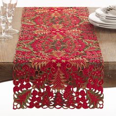 a red table runner on top of a wooden table with plates and silverware in the background