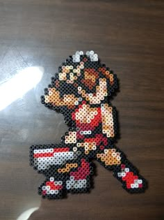 an image of a pixelated character made out of plastic beads on a wooden table