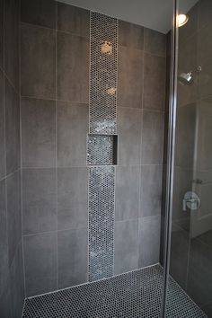 a walk in shower sitting next to a glass door and tiled wall with silver grouting