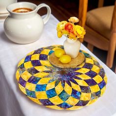 there is a vase with yellow flowers in it on the table next to a plate