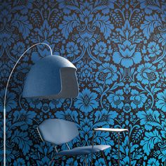 a blue chair sitting in front of a wall with an intricate design on it's side