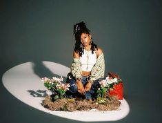 a woman sitting on top of a pile of hay with flowers in front of her